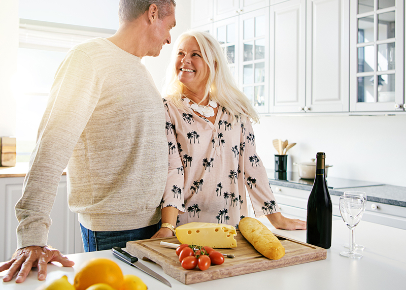 happy couple prepping cheese and wine in kitchen